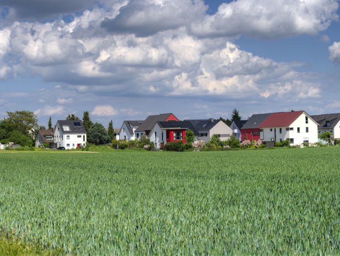 Totalansicht von mehreren Häusern auf dem Land, davor eine große grüne Wiese